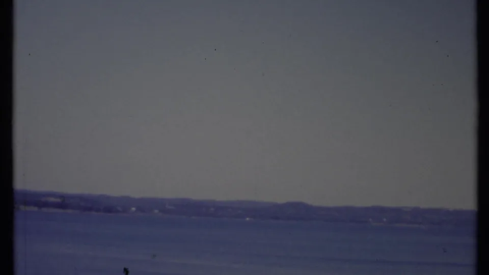 1971 California 8mm still with open sky, calm water, a far shoreline, and visible home-movie grain.