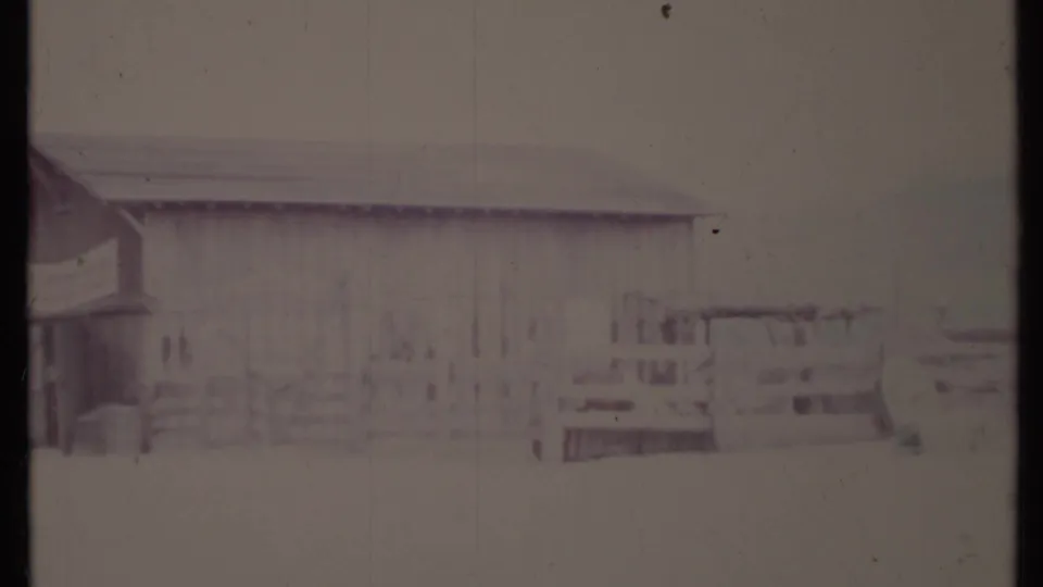 Overexposed 8mm frame from the 1971 California clip, with faint wooden fencing, building edges, and street details still visible.