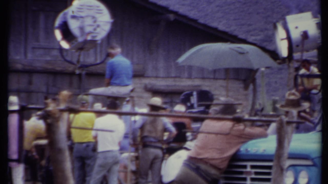 Crew members and studio lights around a rustic barn set.