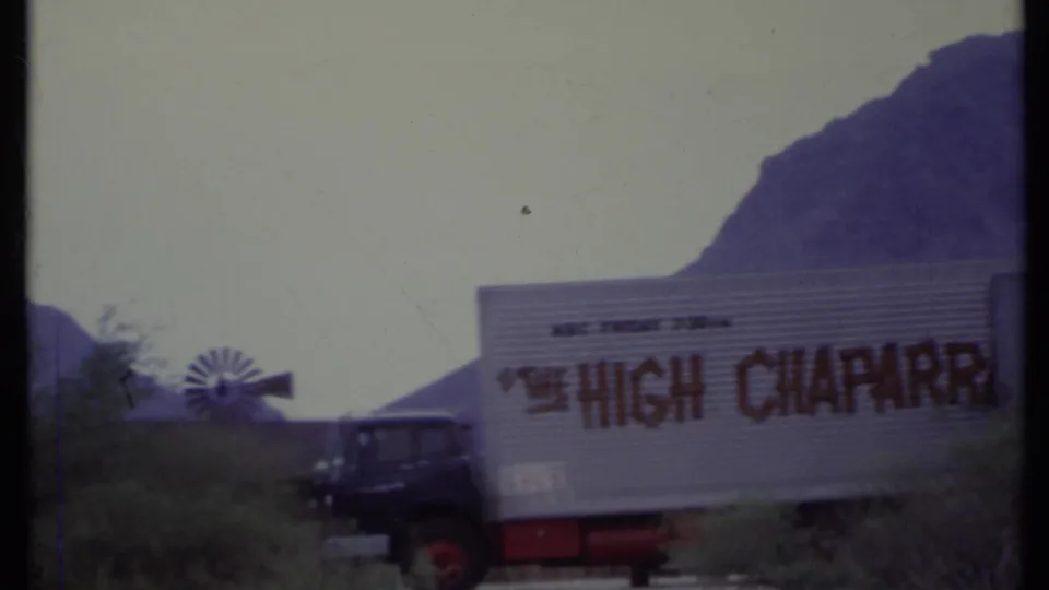 1971 California 8mm frame showing the High Chaparral trailer beside a truck cab, with a small windmill and desert mountains behind it.
