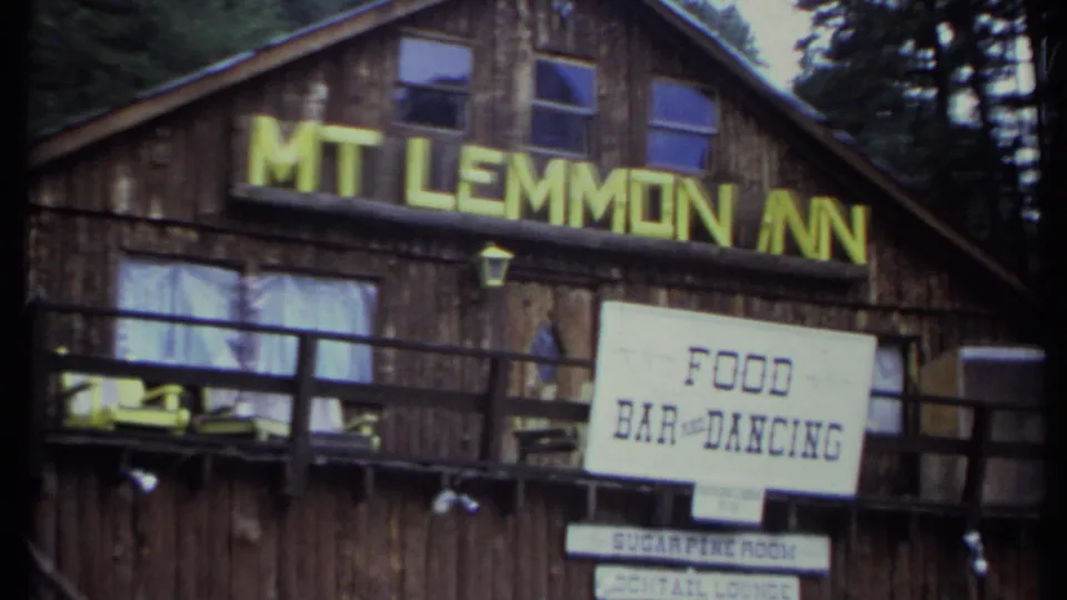 Closer 8mm view of the Mt Lemmon Inn exterior, showing yellow roofline lettering and a food, bar, and dancing sign.