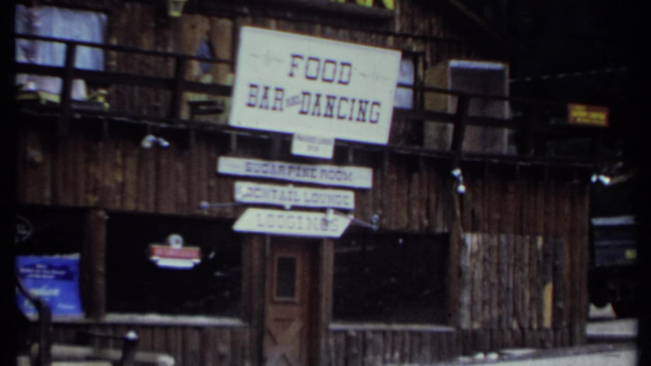 Rustic wooden inn exterior with food bar and dancing sign above directional boards.