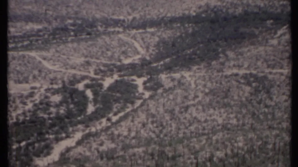 1971 California aerial frame showing sparse desert vegetation, winding tracks, and hazy uneven ground.