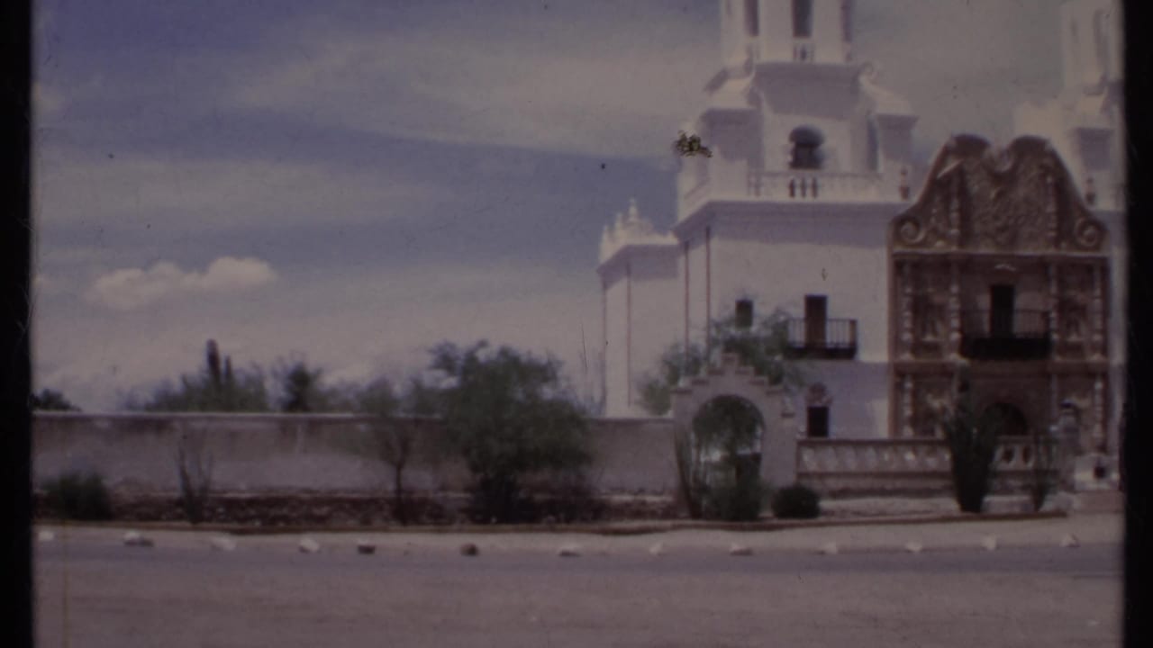 White church with twin bell towers and ornate facade beside a dry roadside.