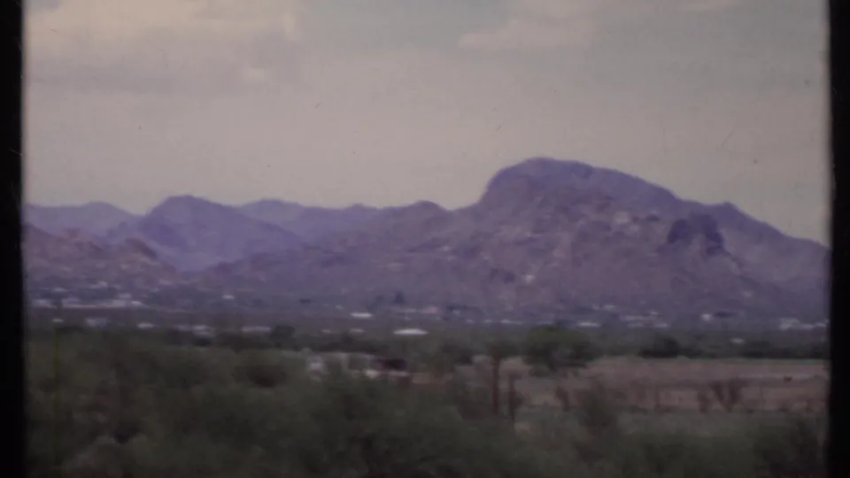 A hazy California desert ridge fills the background, with sparse foreground vegetation and a dark vertical divider from the 8mm scan.