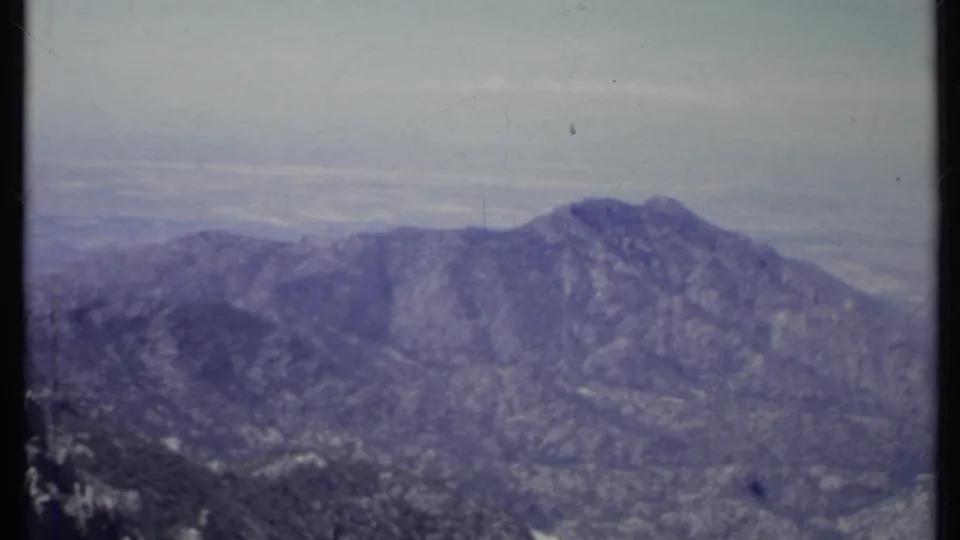 1971 California 8mm landscape frame showing a distant ridge, wooded hills, and hazy sky with visible film fading and grain.