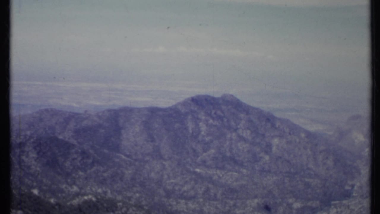 Hazy mountain ridge under a pale sky with 8mm film borders.