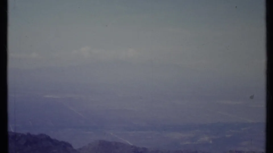 1971 California 8mm frame showing distant mountain peaks under a hazy blue-purple sky with visible film wear.