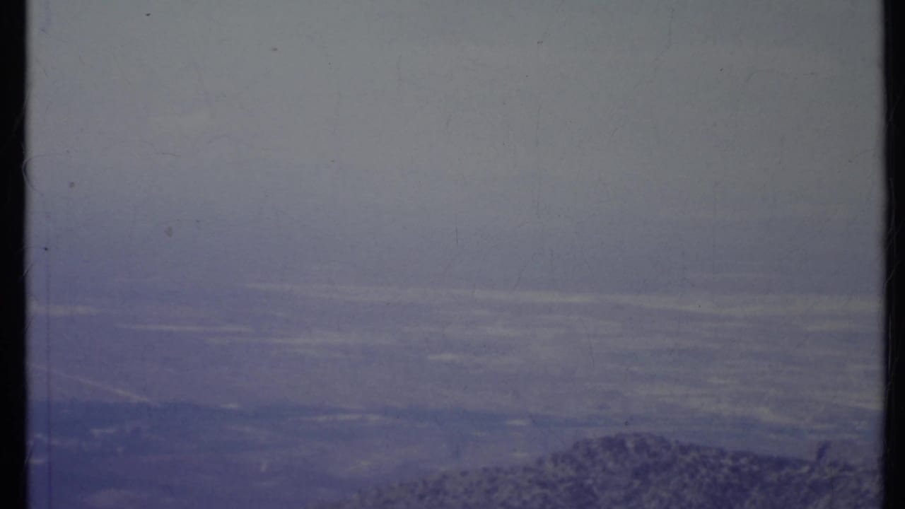 Hazy mountain ridge beneath a pale sky from an elevated viewpoint.