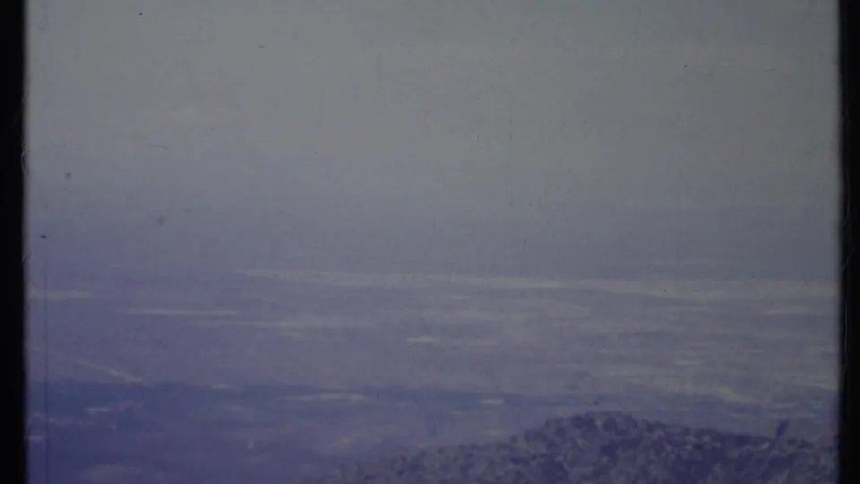1971 California 8mm frame showing a hazy mountain ridge and distant valley under a pale overcast sky.