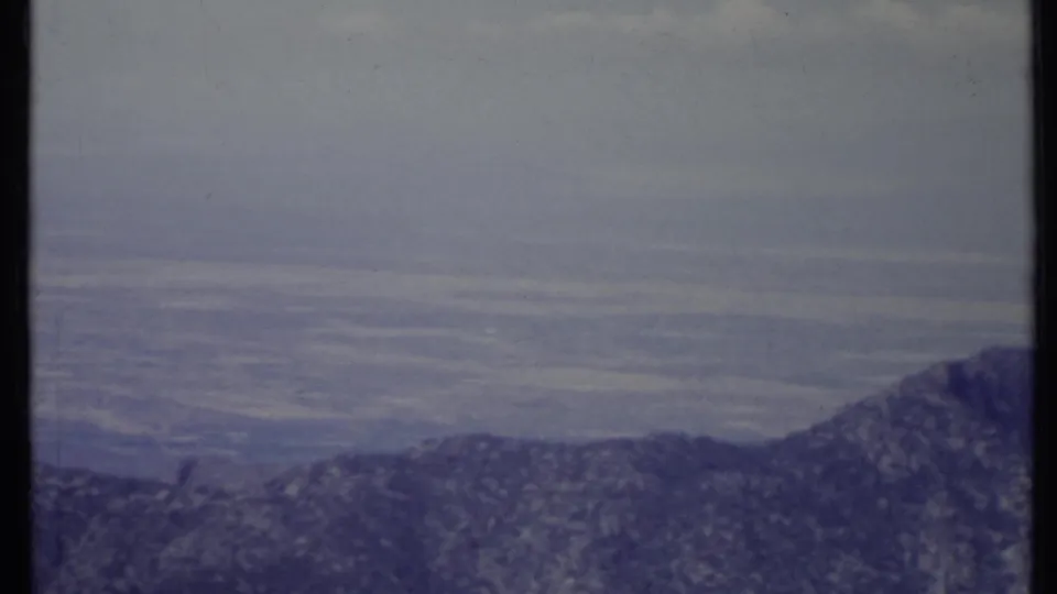 1971 California 8mm frame looking over a low mountain ridge toward a broad, hazy valley landscape.