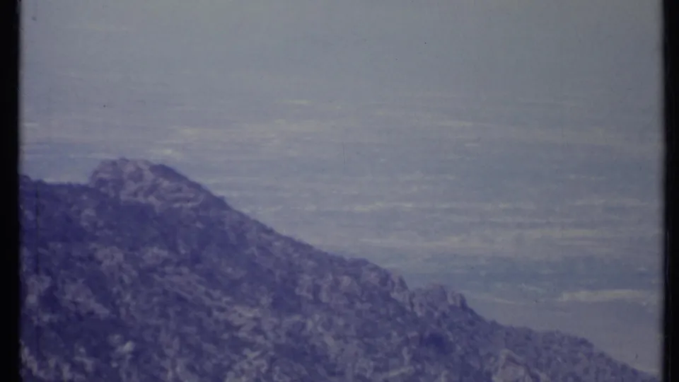 1971 California 8mm view of a rocky slope overlooking a wide, hazy valley below.