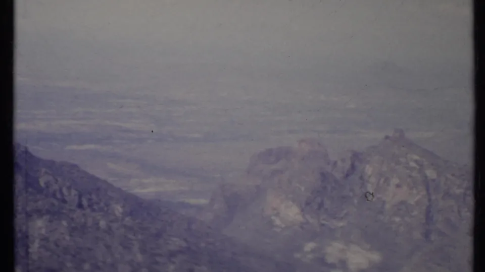 1971 California 8mm frame showing layered mountain slopes and a softened valley view through atmospheric haze.
