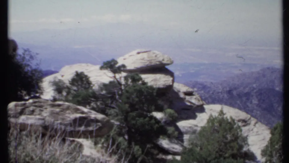 1971 California 8mm view of a distinctive capstone rock formation at a mountain overlook above a hazy valley.