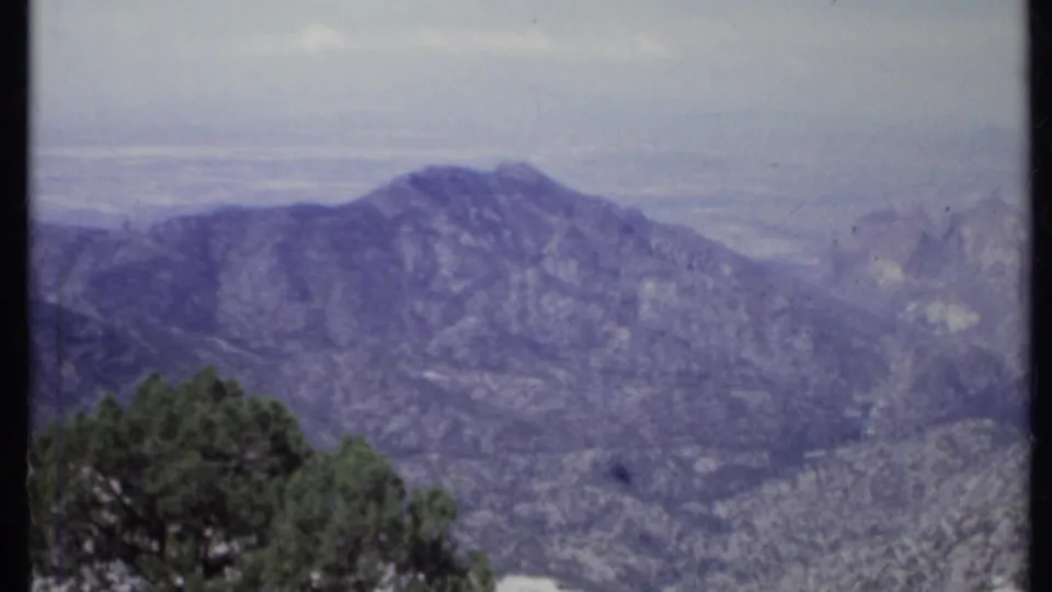 1971 California 8mm view of a rugged distant ridge, foreground trees, and a pale hazy sky.