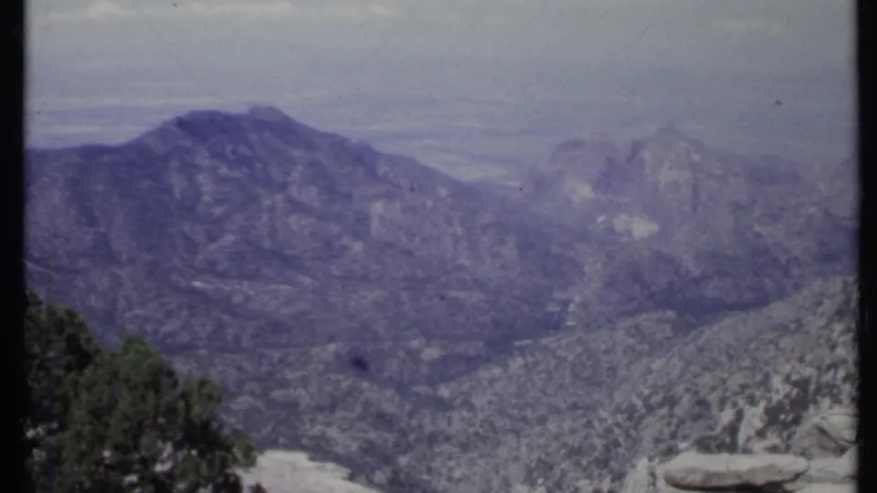 1971 California 8mm view of rocky mountain ridges with foreground trees, pale stone, and boulders.