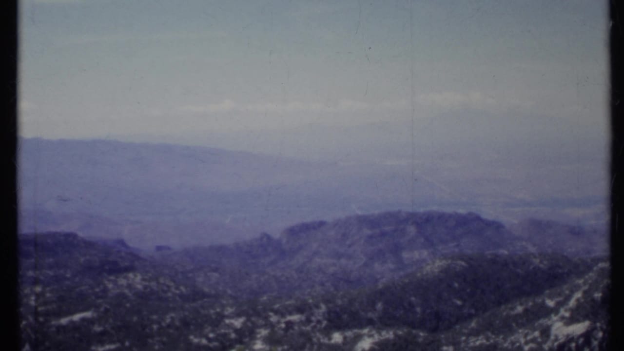 Hazy mountain ridges and rocky slopes beneath a pale sky.