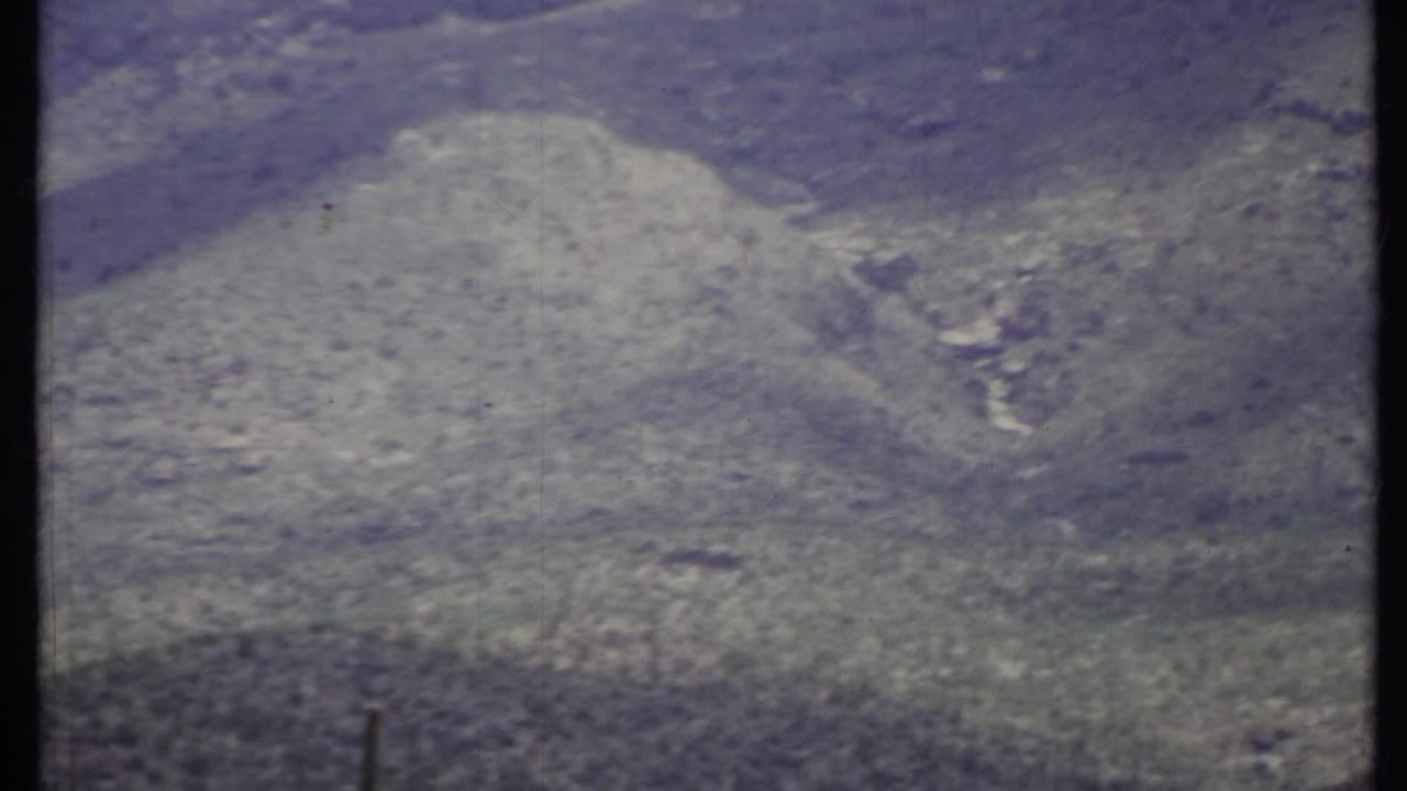 Pale rocky desert hills seen through a soft, grainy 8mm frame.