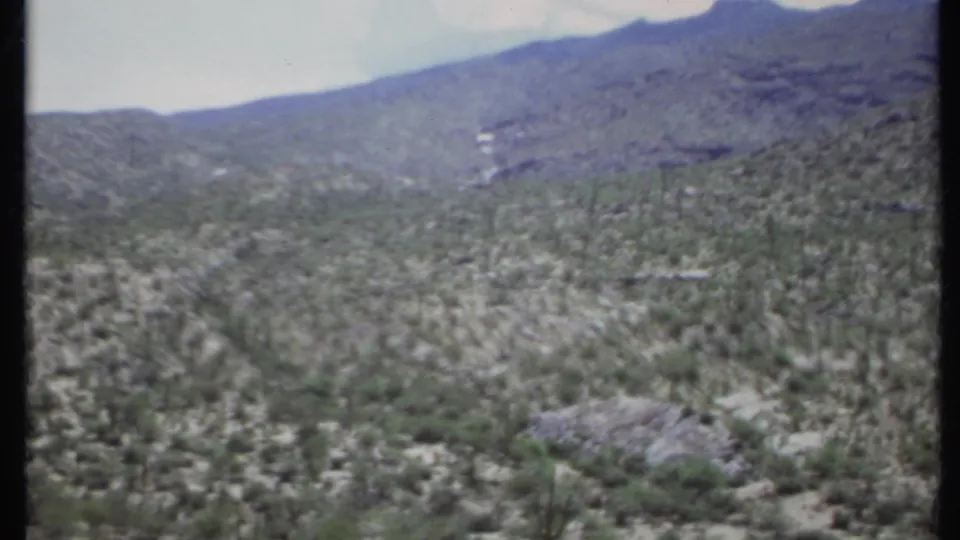 Wide 1971 California desert landscape with a shrub-covered valley, cactus forms, and distant mountain slopes.