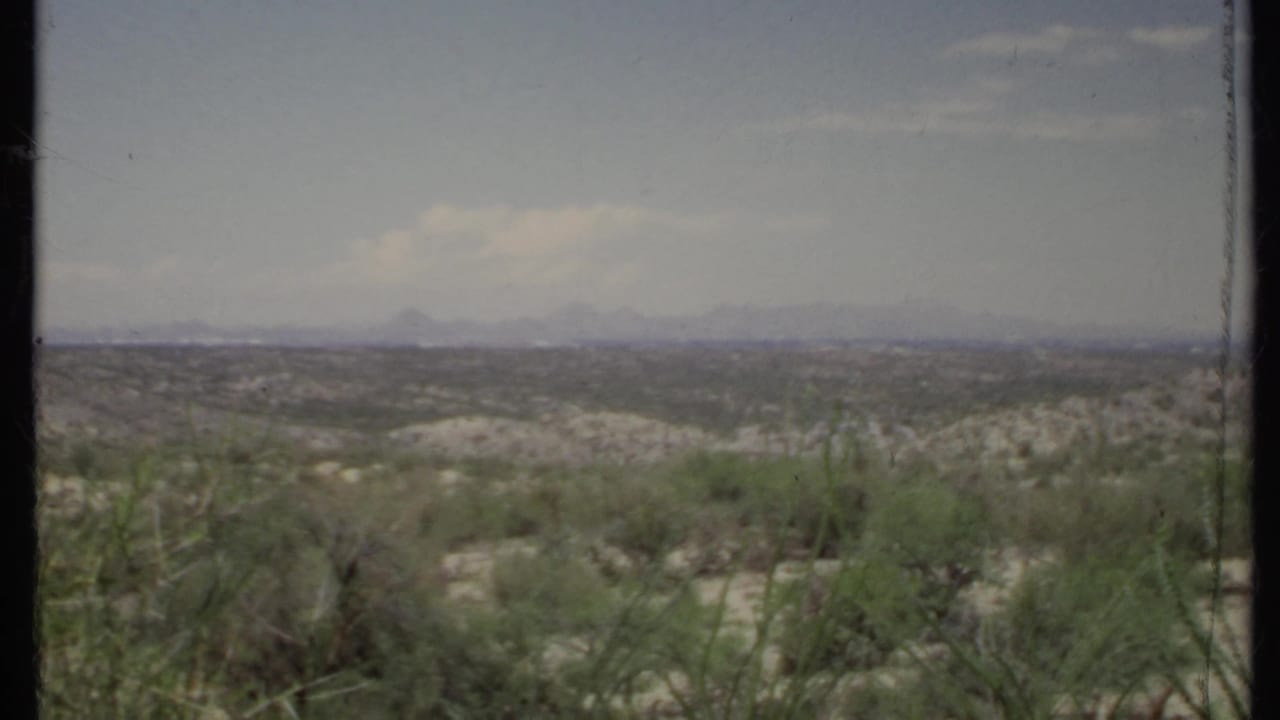 Sparse desert vegetation fills the foreground with low hills and mountains beyond.