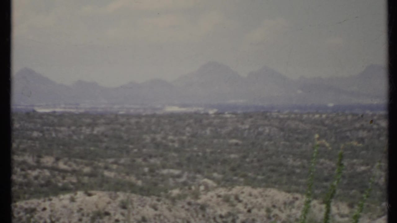 Desert valley and distant mountain range seen through a soft, grainy frame.