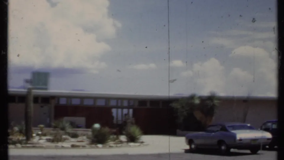 1971 California 8mm frame showing a modern house facade, cacti, driveway, and a parked vintage car.