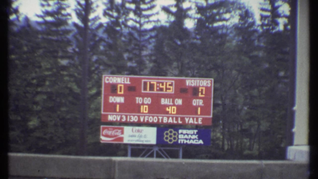 Scoreboard for Cornell and Yale with trees behind it.