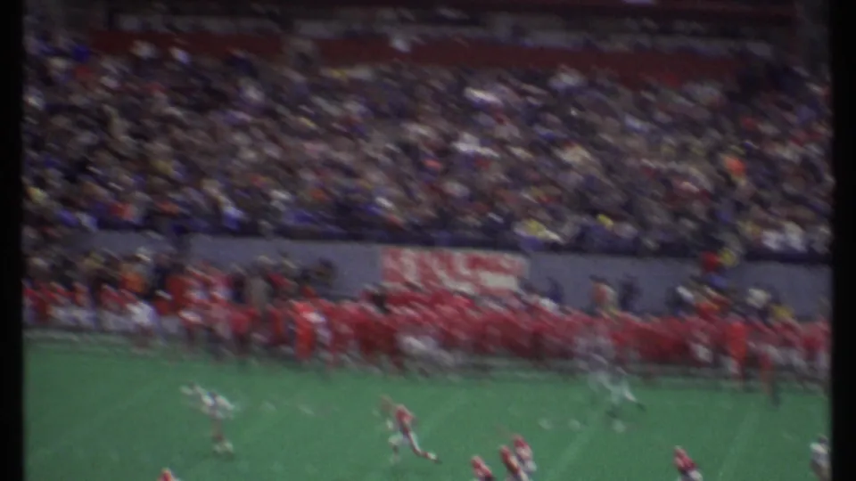 A 1979 Ithaca football game appears in soft 8mm footage as players run downfield before packed bleachers.