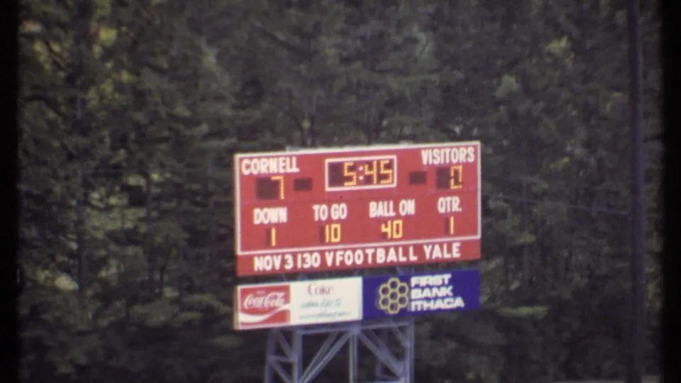 Closer view of the Cornell football scoreboard in Ithaca, with the 7-0 score, game details, and sponsor signs visible below.