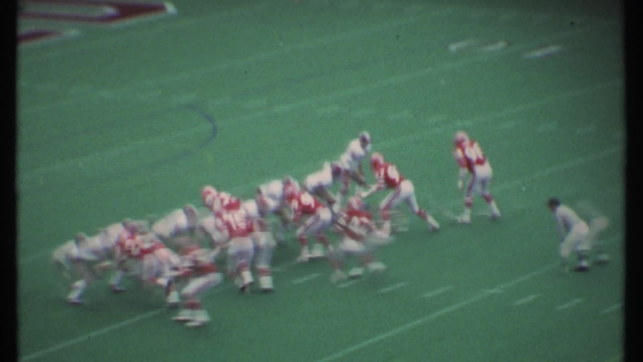 1979 Ithaca, New York football players in red and white uniforms set for a play on a green artificial turf field.