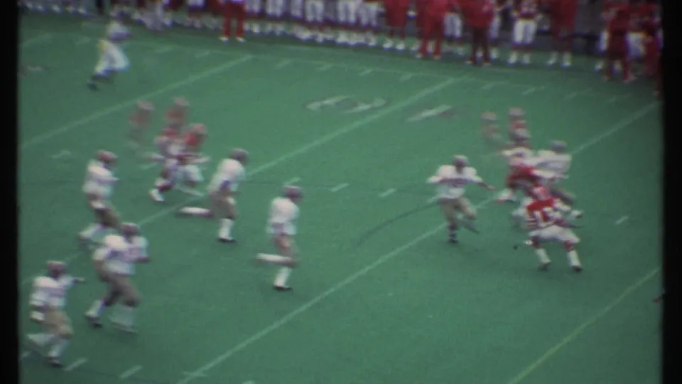 1979 Ithaca football game footage showing red and white uniformed players moving through a play on the field.