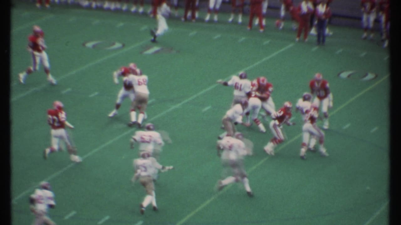 A football play develops near midfield with players blocking and running.