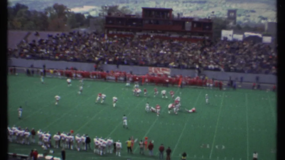 Wide 1979 Ithaca stadium view with football players on the field, crowded stands, and a press box in the background.
