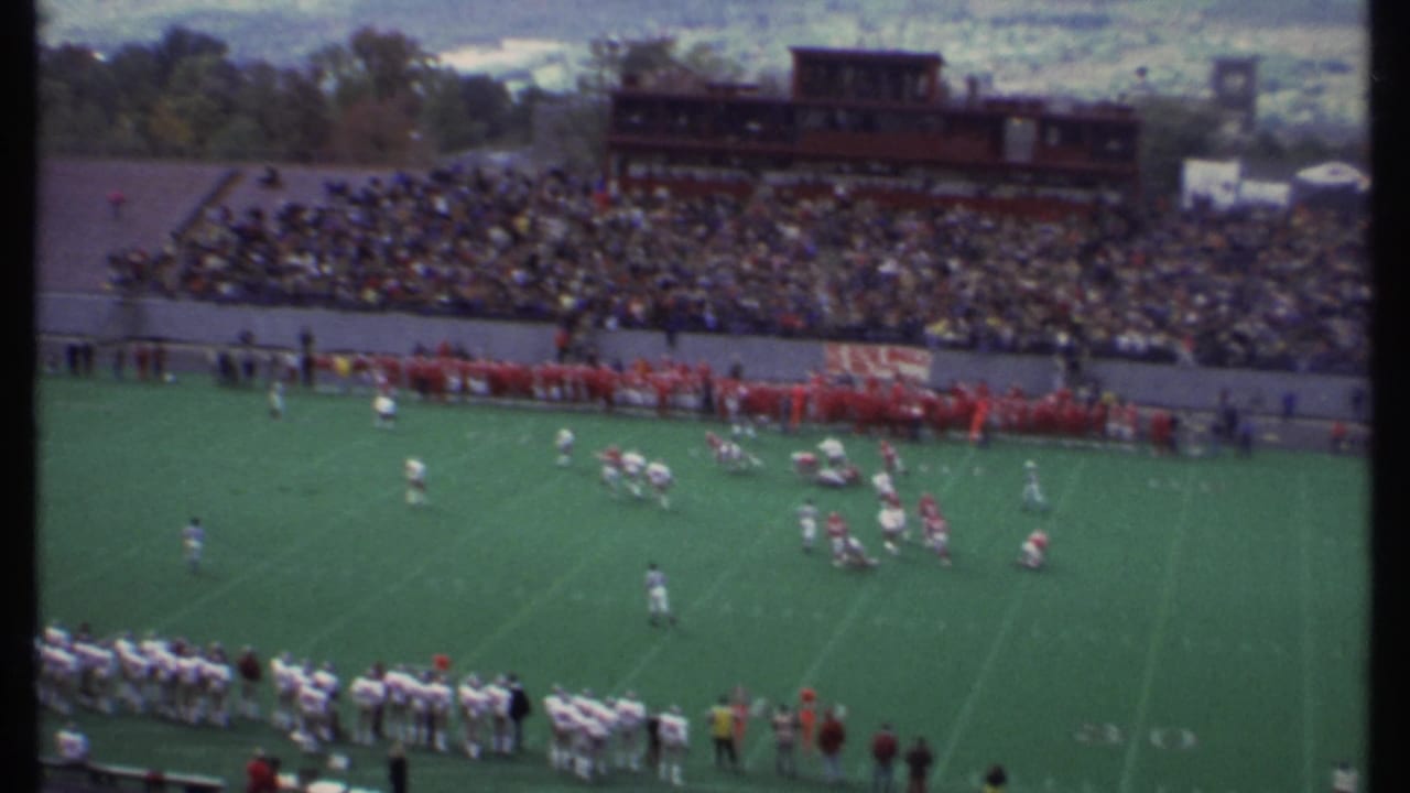 1979 Ithaca football game seen from the stands, with red and white teams on the field and a crowded stadium behind them.