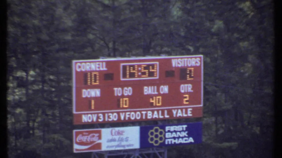 Scoreboard at a Cornell football game in Ithaca shows Cornell leading visitors 10 to 2, with sponsor signs below.
