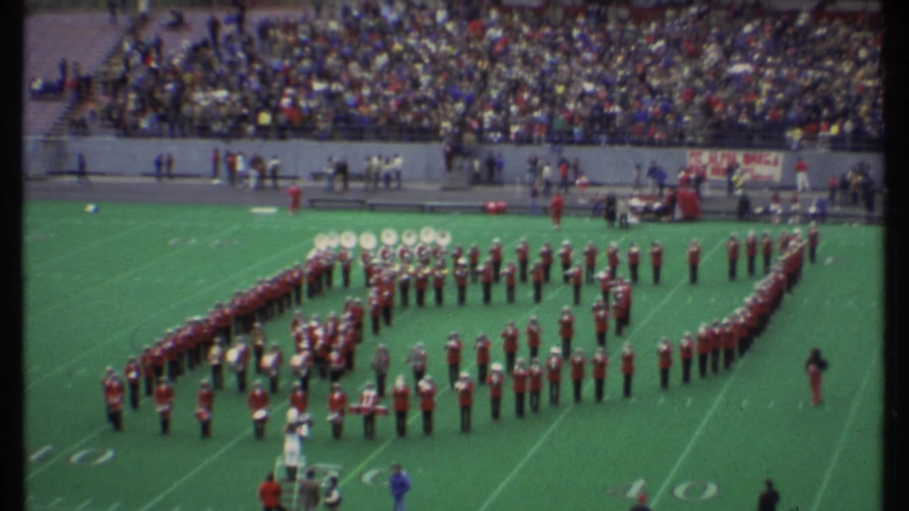 Wide stadium view of a marching band forming shapes on a football field.