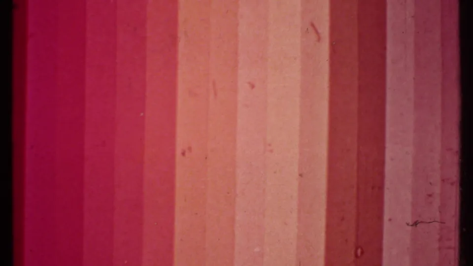 1979 8mm frame showing vertical magenta-orange exposure bands, dust, grain, and a dark film border.
