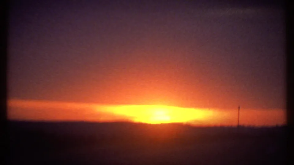 1979 8mm sunset view in Ithaca with bright yellow-orange light spreading across the low horizon.