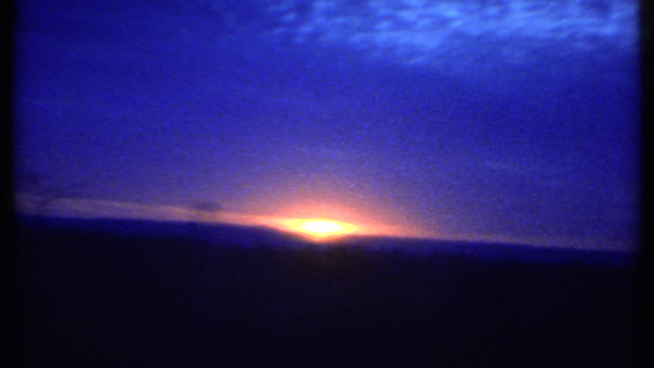 Bright sunrise glow near the horizon under a broad blue sky.