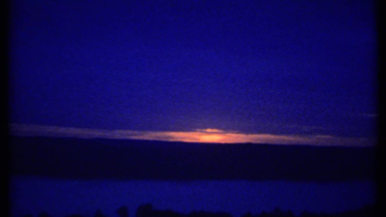 Distant sunset glowing behind clouds over a dark blue horizon.