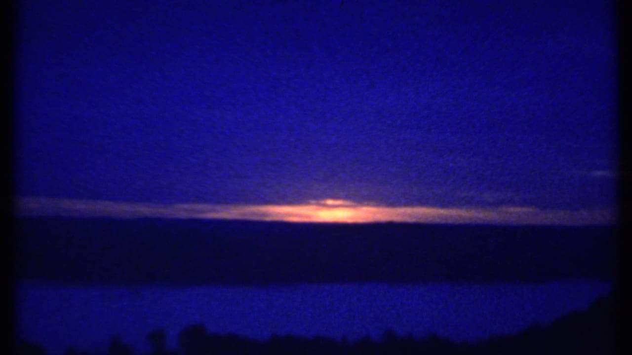 Blue-toned horizon with a narrow orange sunset under clouds.