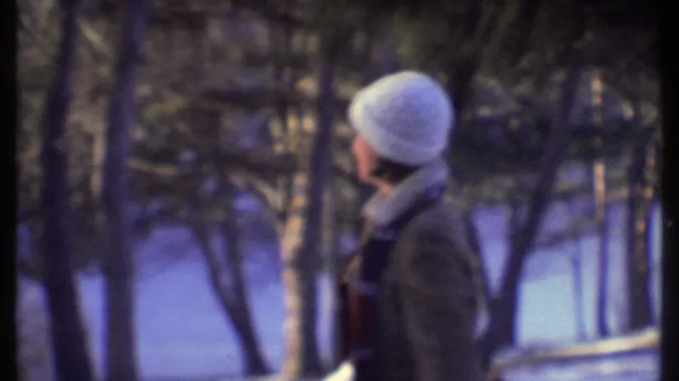 A teenager in a white knit hat and winter coat looks across a snow-covered wooded park in Ithaca, New York, in 1979.
