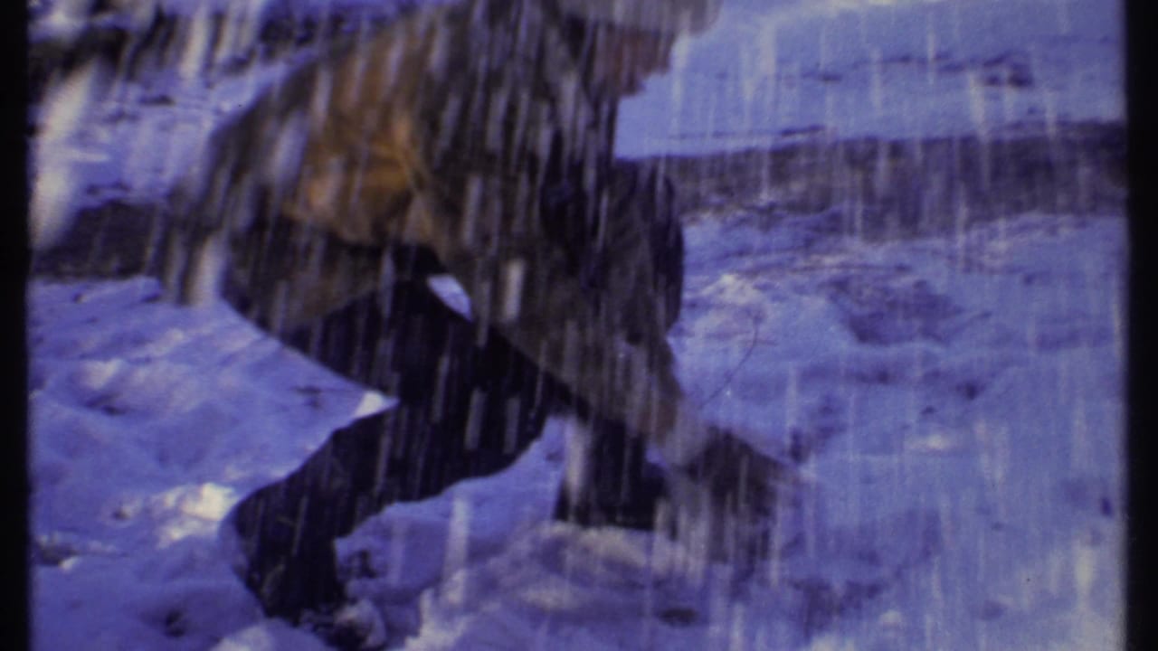 A bundled figure moves through snow or falling snow spray in the 1979 Ithaca winter home-movie scene.