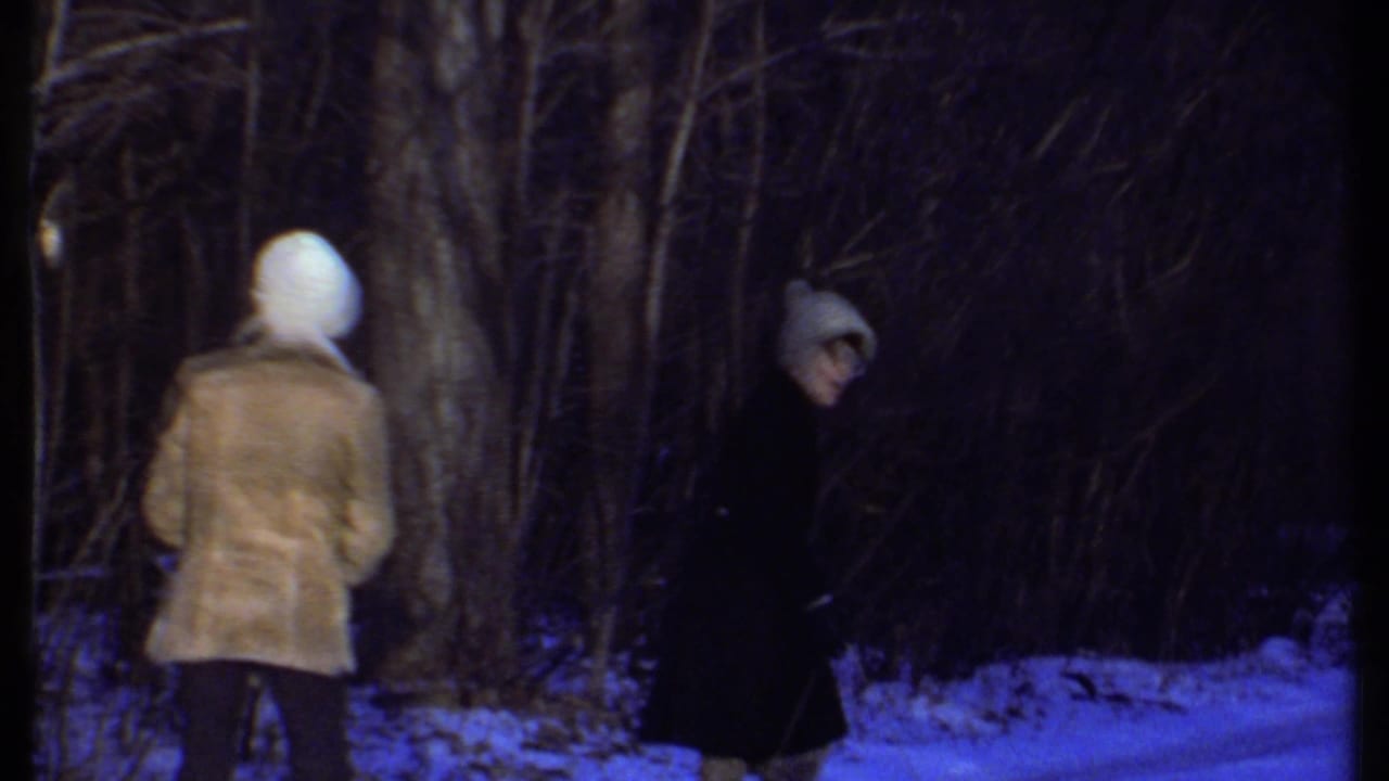 In supported 1979 Ithaca home-movie footage, two women in knit caps and coats stand in a snowy wooded area.