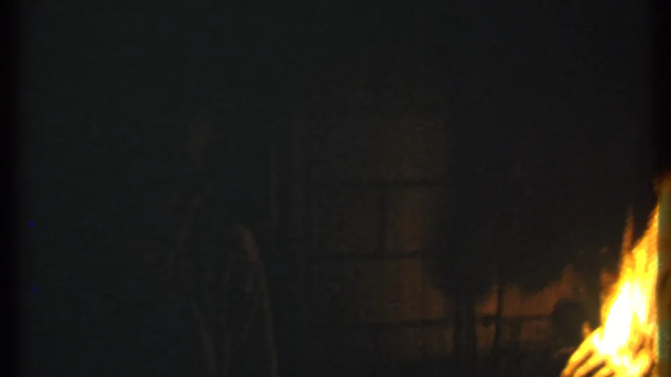1979 Ithaca 8mm frame showing a bright nighttime fire with indistinct people and dark outdoor surroundings.