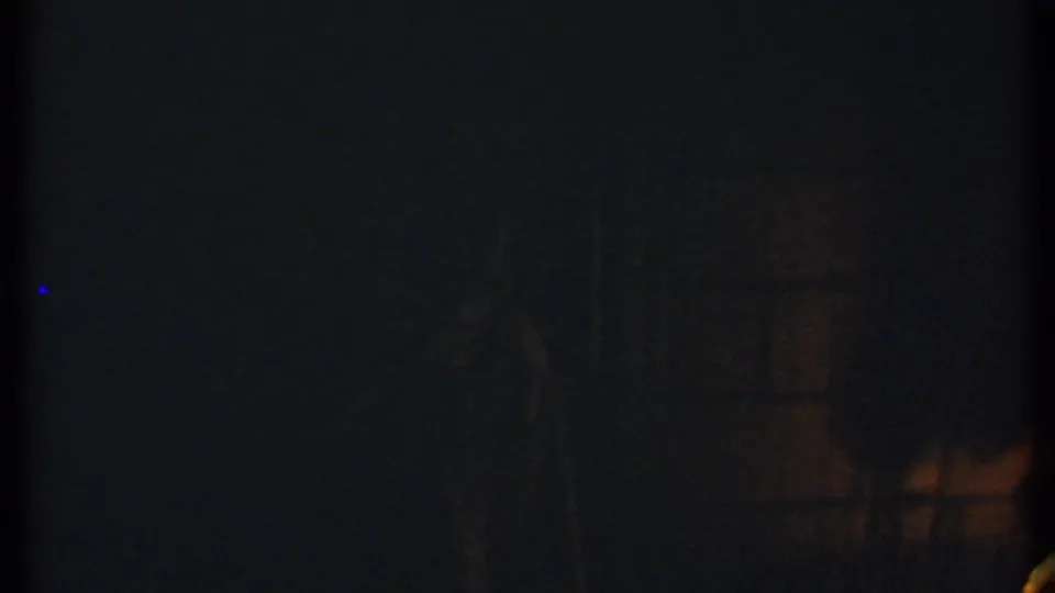 1979 Ithaca 8mm frame with dim firelight at night and indistinct silhouettes in a dark setting.