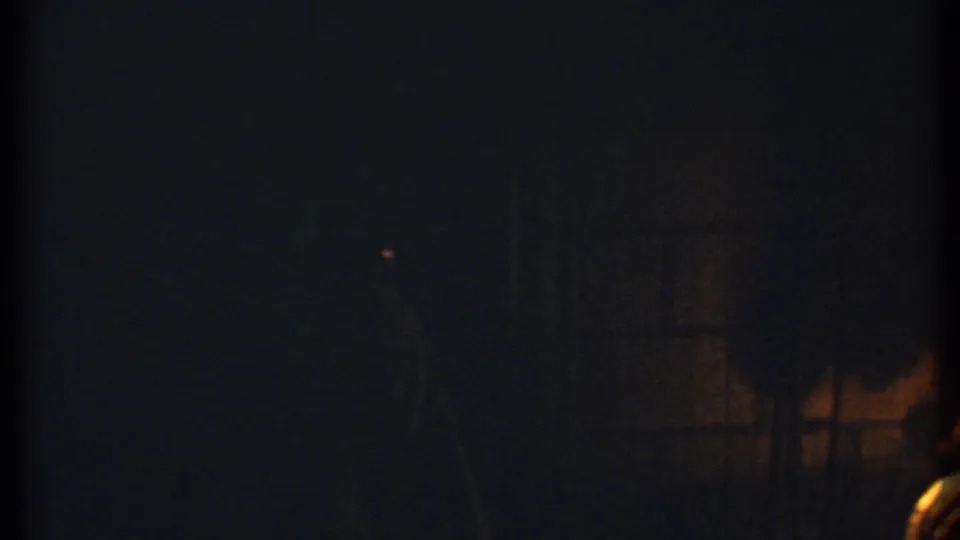 1979 Ithaca 8mm frame showing a very dark nighttime fireplace scene with faint warm firelight and visible film grain.