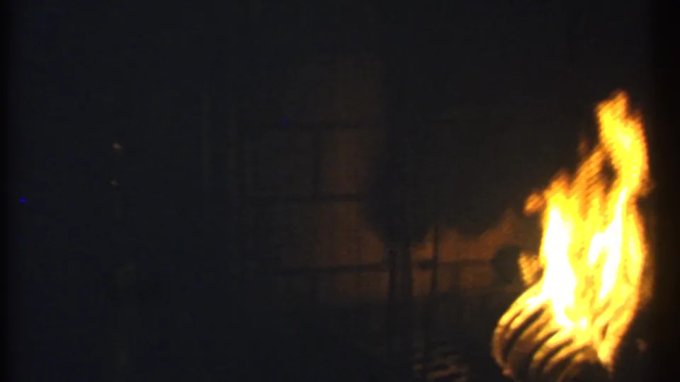 1979 Ithaca 8mm frame with bright flames at the right side, surrounded by a mostly dark fireplace interior.