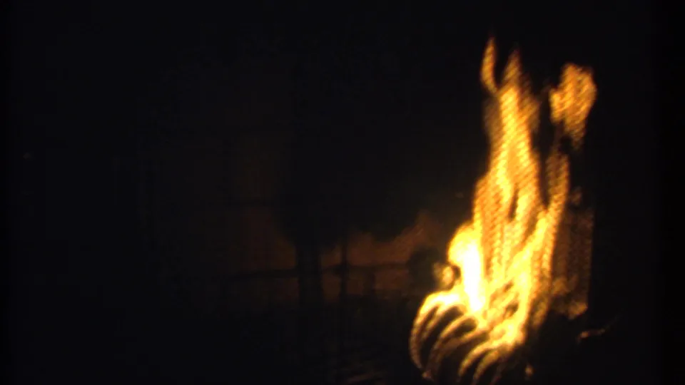 1979 Ithaca 8mm frame showing tall, blurred flames rising in a dark fireplace scene with warm orange highlights.