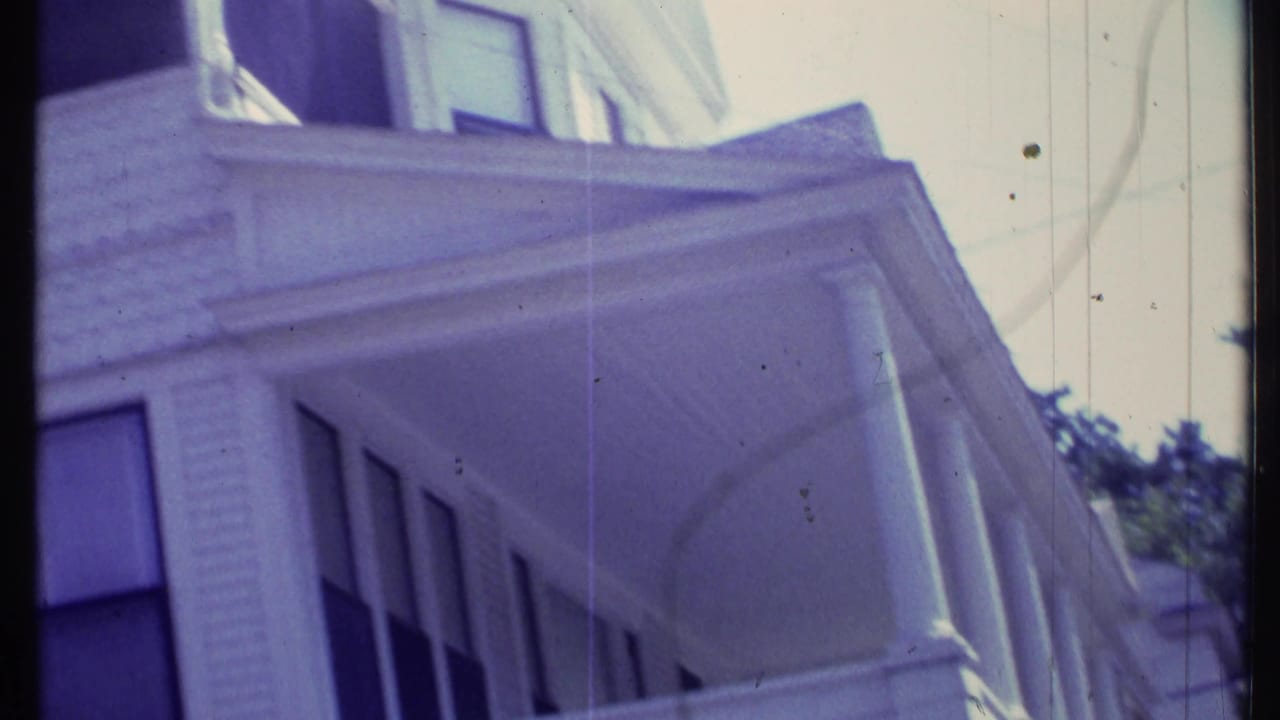Soft 8mm view of a white Vermont house exterior, showing upper windows, porch roofline, siding, and columns.